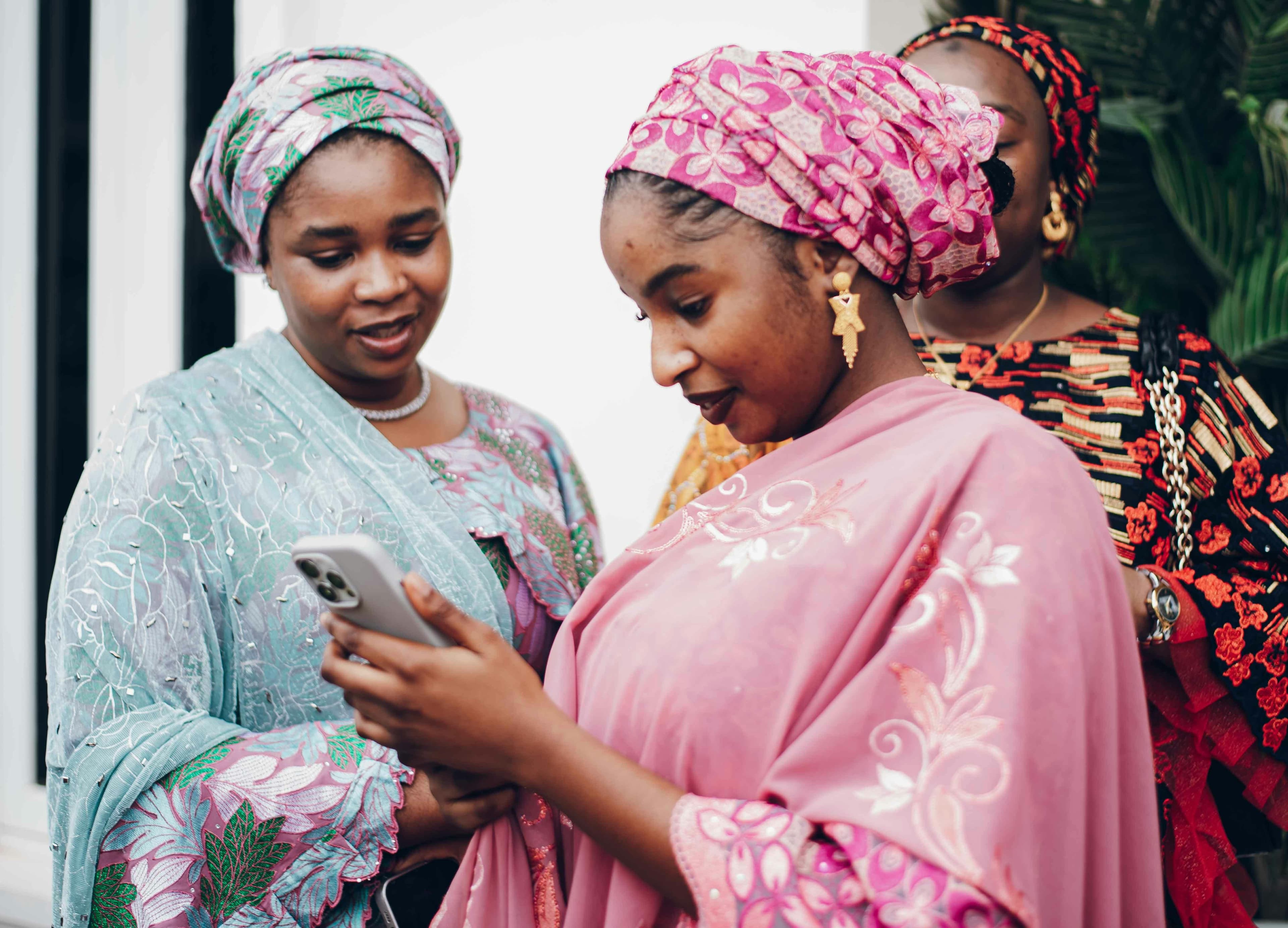 Deux femmes en tenues traditionnelles regardant un iPhone ensemble